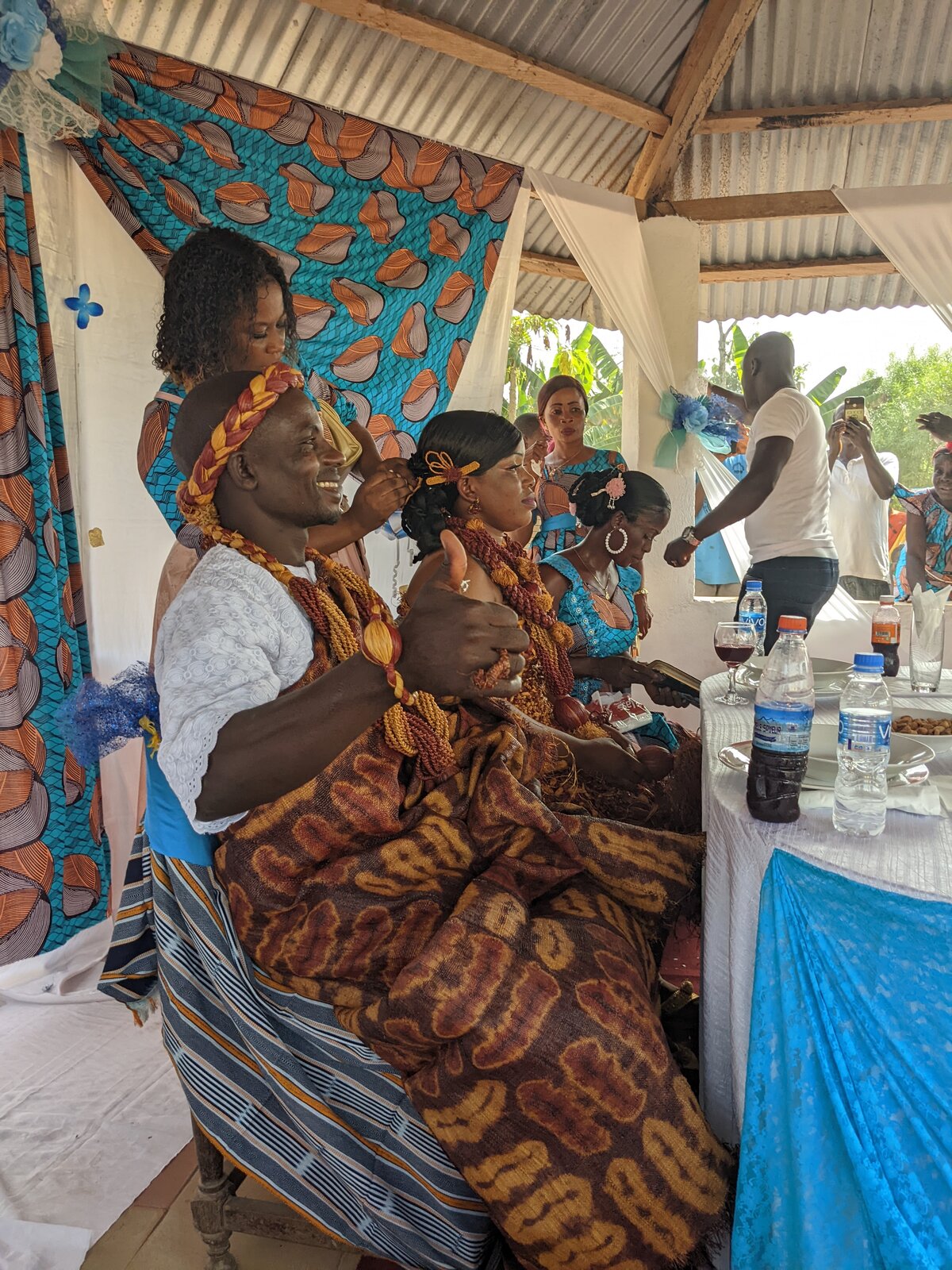 The couple, wearing traditional outfits, sit at the head table at the reception